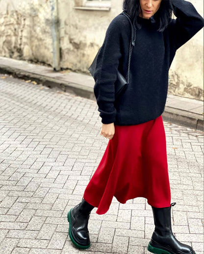 A woman in a black sweater and red skirt carries the Chain Shoulder Bag - Black, a sleek leather accessory with a matte chain strap and chic design.