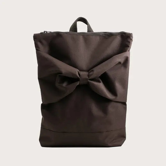 A brown waterproof MUNI backpack with a large bow detail, ideal for daily use. Features adjustable straps, zipper closure, and compartments for a 13 laptop. Dimensions: 38cm height, 34cm width.