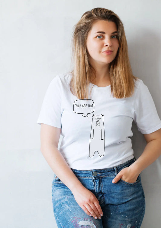 A woman in a white oversized t-shirt with a cartoon bear and speech bubble print. Product: You Are Hot T-Shirt made of organic cotton. Size chart: XS - XL.