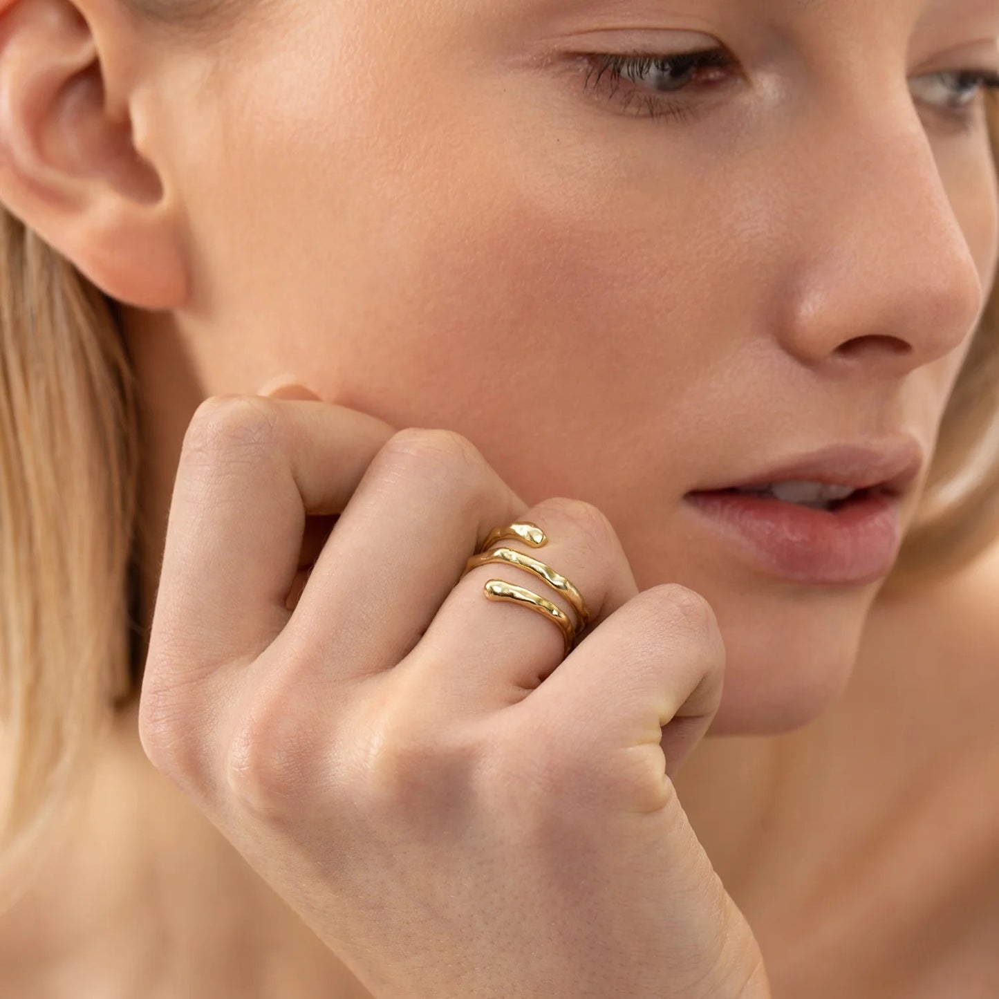 A close-up of a woman's hand wearing the resizable Ring SPIRAL - Gold by ONEHE, showcasing elegant 925 sterling silver with 18k gold plating. Hypoallergenic and adjustable for sensitive skin.