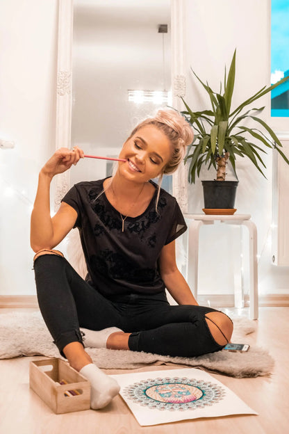 A woman sitting on the floor with a pendant necklace that reads ANYTHING IS POSSIBLE and MAKE IT HAPPEN. Necklace length: 50 cm. Available in silver, rose gold, gold.