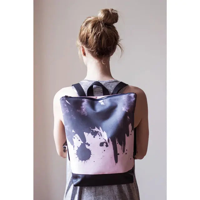 A woman with a Watercolor backpack, featuring velvet top with printed design, sturdy navy blue bottom, and laptop pocket. Stylish and practical for office or park.