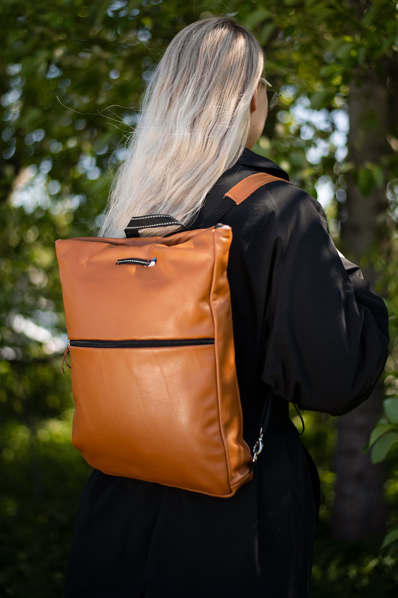 Handmade Barbara Leather Backpack - Calvados, crafted from furniture industry leftovers, worn by a woman with long blonde hair. Made in Estonia, eco-friendly, durable.