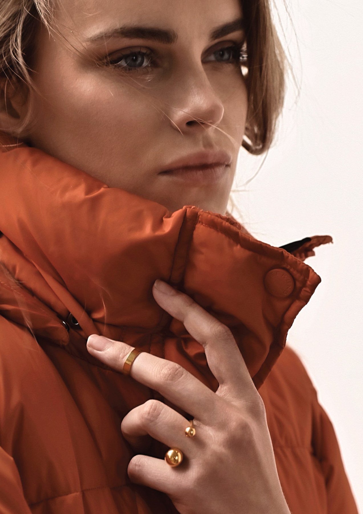 A woman's hand wearing a gold bomb ring with hollow bubbles on a band. Made of sterling silver coated in 24K gold. Multisize for a perfect fit.