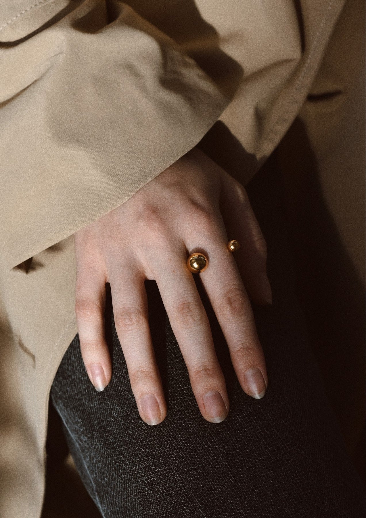 A hand wearing a Gold plated bomb ring with two hollow bubbles on a band, made of sterling silver coated with 24K gold plating. Multisize options available: S, M, L. Hand-made sustainably in Lithuania.