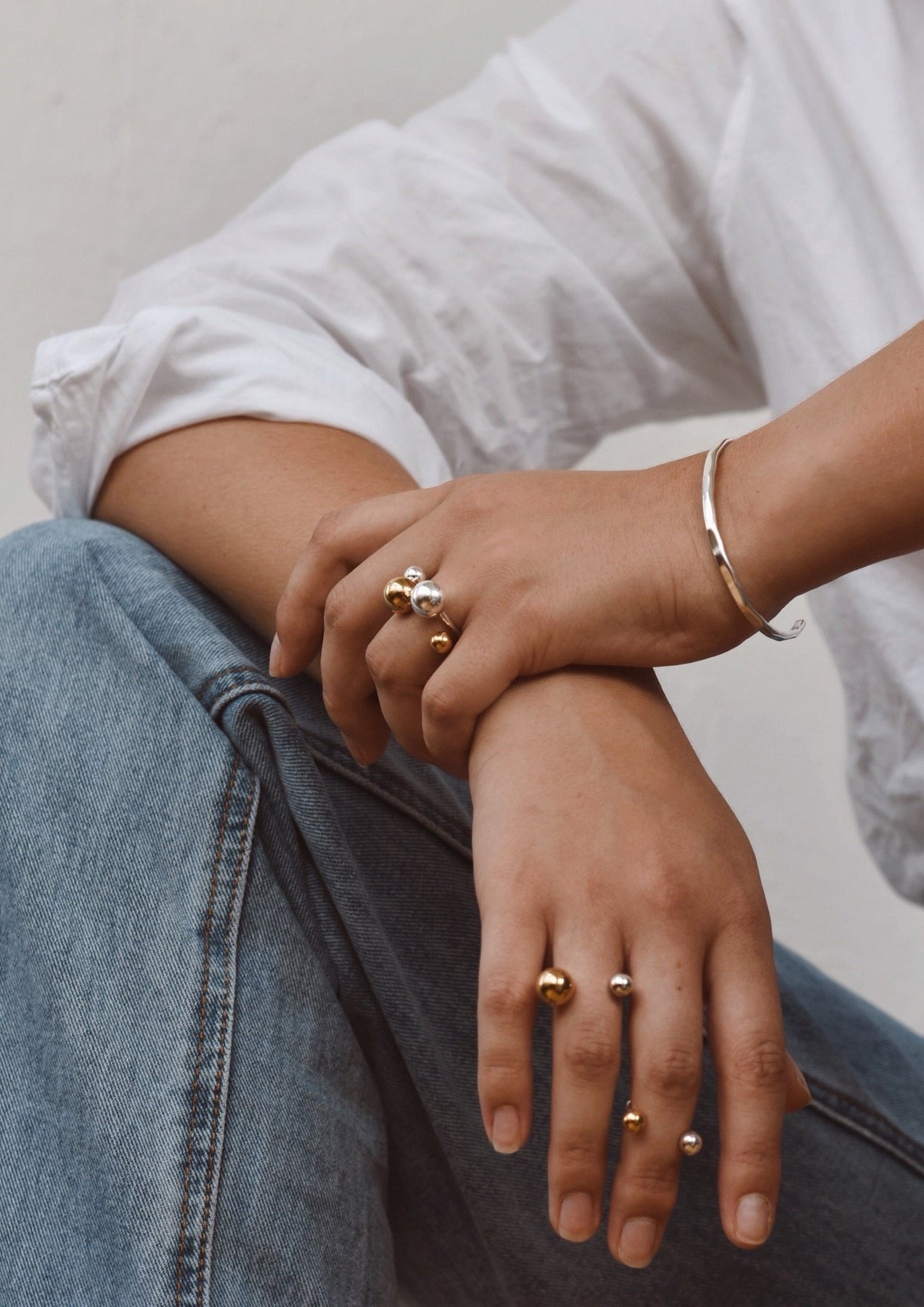 A close-up of a person's hand with a Big Bomb Multisize Ring in Gold, featuring a bold design with hollow bubbles on a band. Handmade with 24K gold-plated sterling silver.