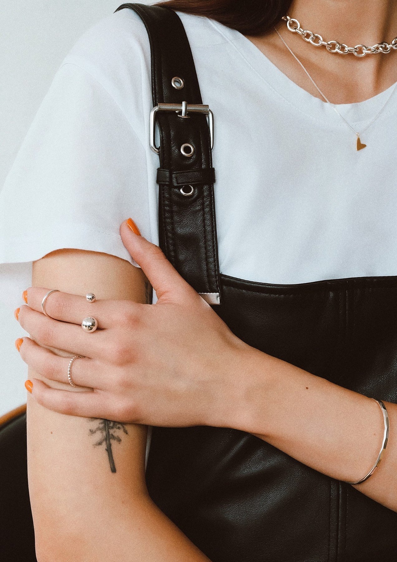 A person wearing a white shirt and black overalls showcasing the Big Bomb Multisize Ring - Silver. Hand-made in Lithuania, this sterling silver ring features 6mm and 10mm hollow bubbles on a 1.8mm band.