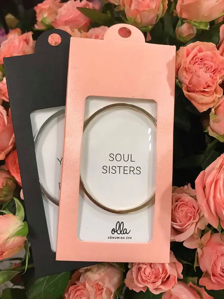 A silver bracelet in a pink and black box, engraved with Soul Sisters. Adjustable, durable, and lightweight. Width: 3 mm. Available in silver, rose gold, gold.