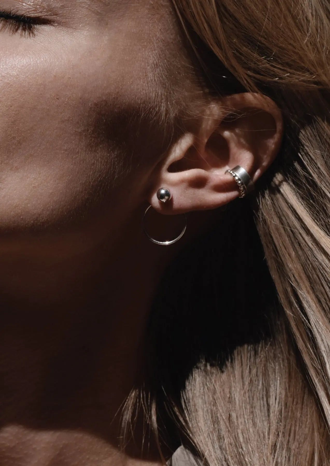 Close-up of a woman's ear with a silver ball earring in the front and a ring at the back. Sterling Silver Chord Earrings: 1.2mm band, 18.2mm circle diameter, 3mm bead, push-back clasps.