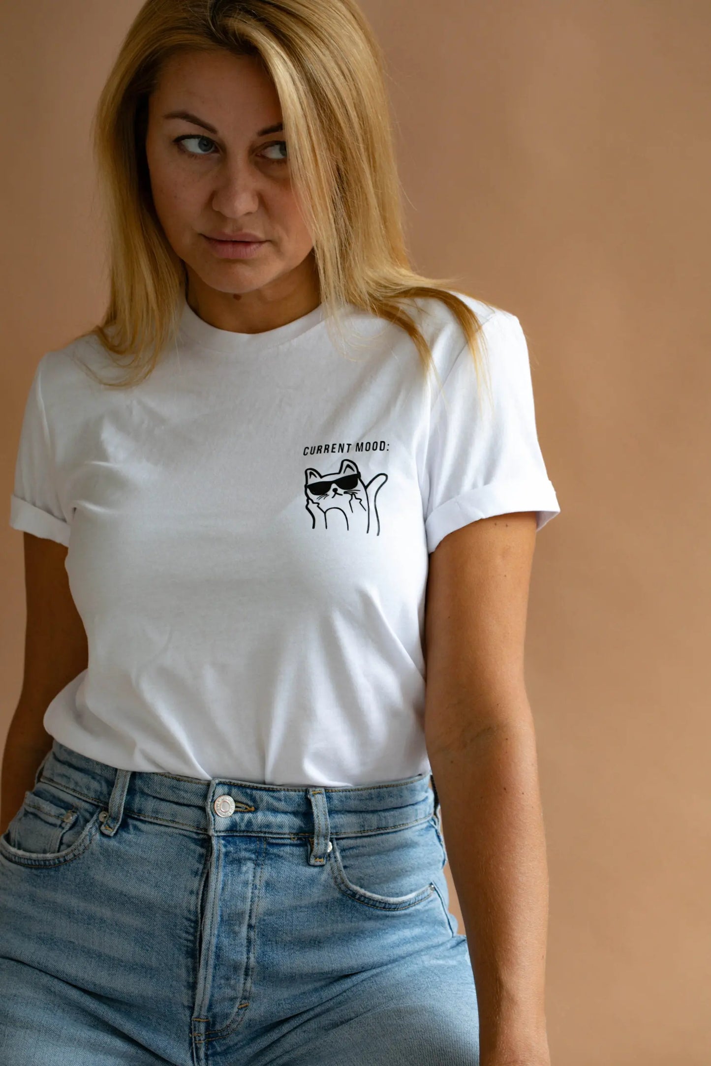 A woman in an oversized white t-shirt with a cat print, paired with blue jeans. The shirt features 'Current Mood' text. Product: Current Mood T-Shirt With Kitty.