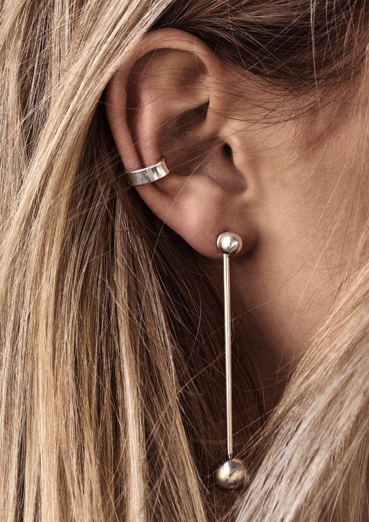 A close-up of a woman's ear featuring the Flat Ear Cuff in Sterling silver by NO MORE cuff studio. Hand-made sustainably in Lithuania, no piercing required.