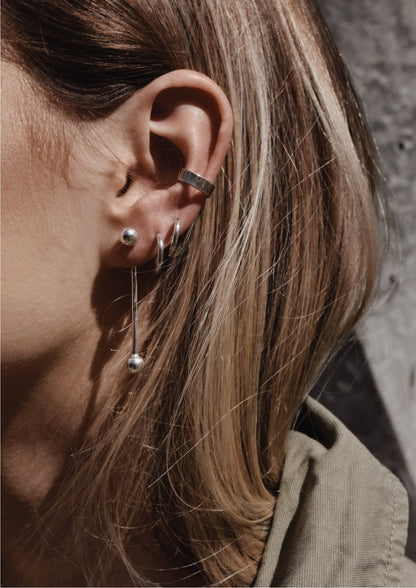 A close-up of a woman wearing a Flat Ear Cuff in Sterling silver, showcasing a sleek design for non-pierced ears. Handcrafted sustainably in Lithuania.