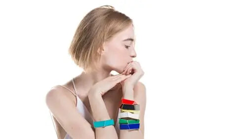 A woman with her chin on her hand, showcasing the Folded Bracelet by Lisa Kroeber Jewellery. Handcrafted in Europe from powder-coated brass, exuding elegance and sophistication.