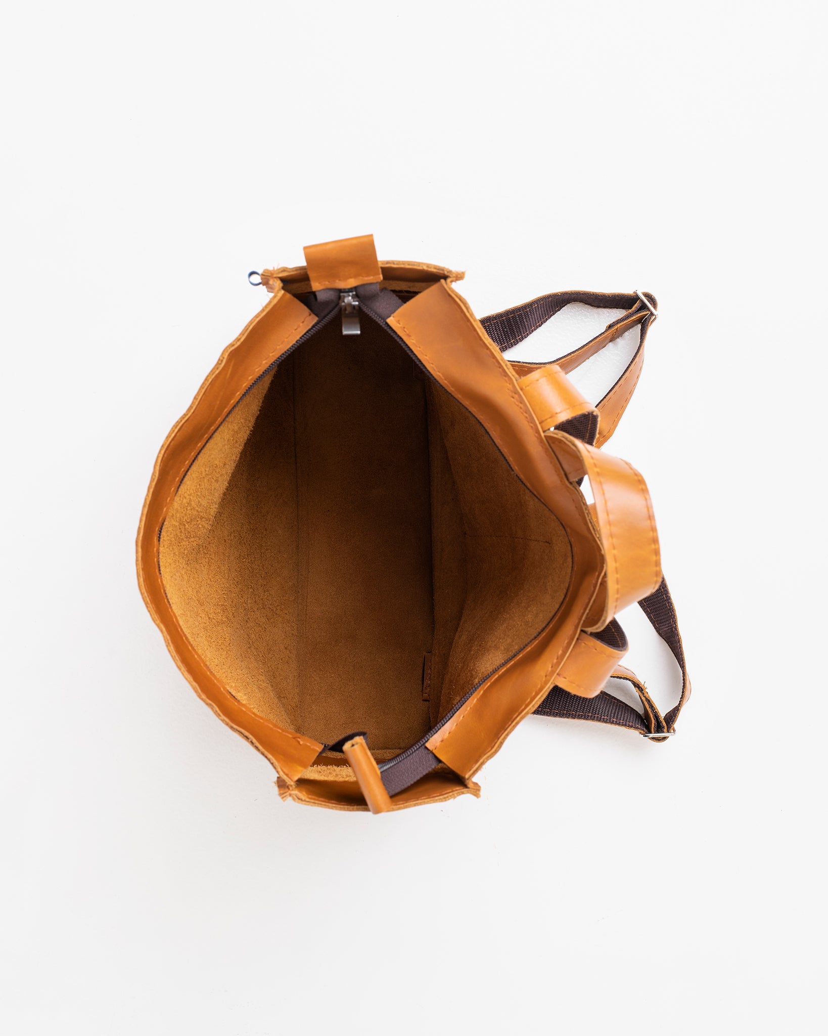 Handmade Folk 2 leather backpack in caramel, crafted from high-quality furniture leftovers. Unique design with large pocket and two smaller ones. Made in Estonia. Dimensions: 30 x 30 x 9.5 cm.