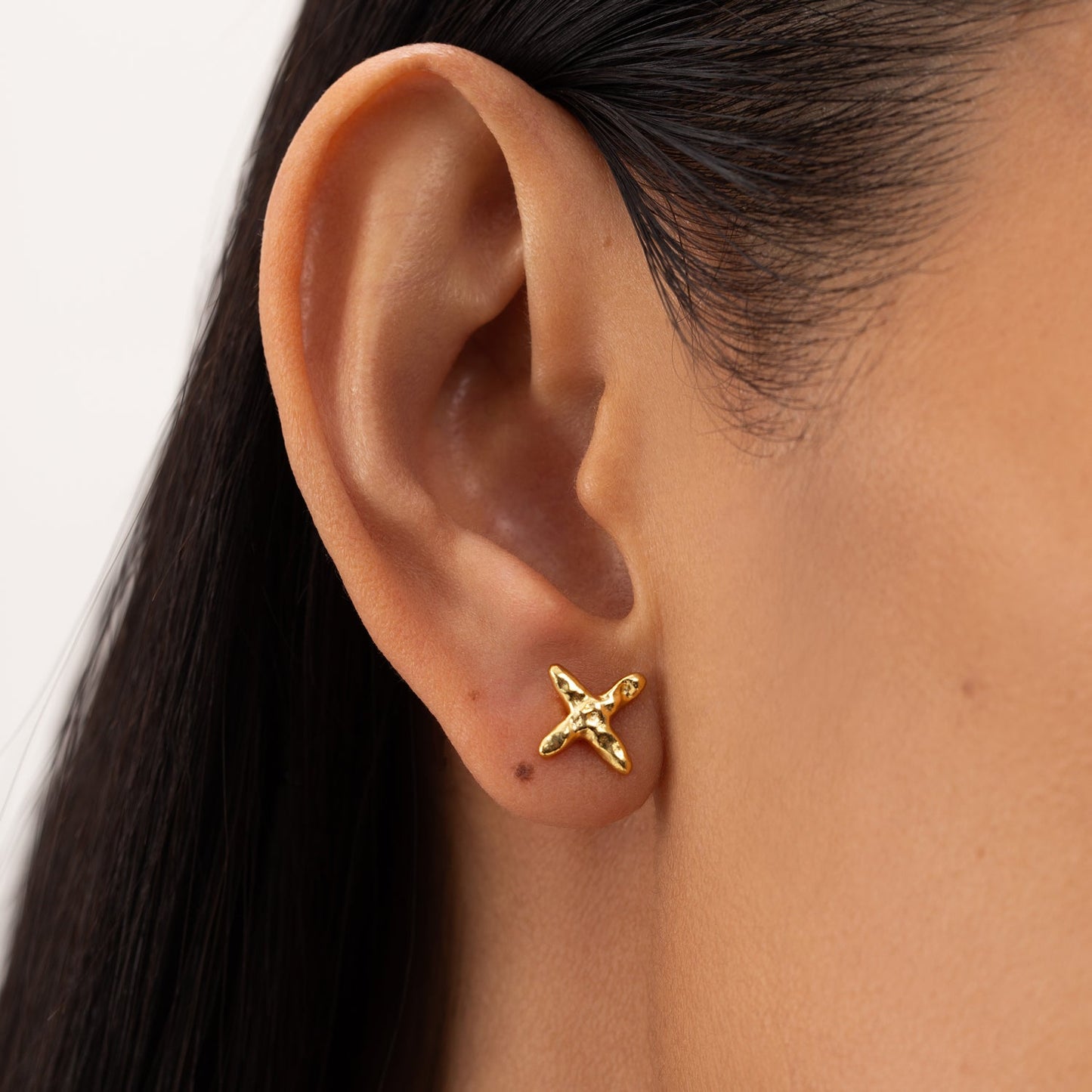 Close-up of ONEHE sustainable Stud Earrings CROSS in 18k gold, hypoallergenic and minimalist design, made from recycled silver.