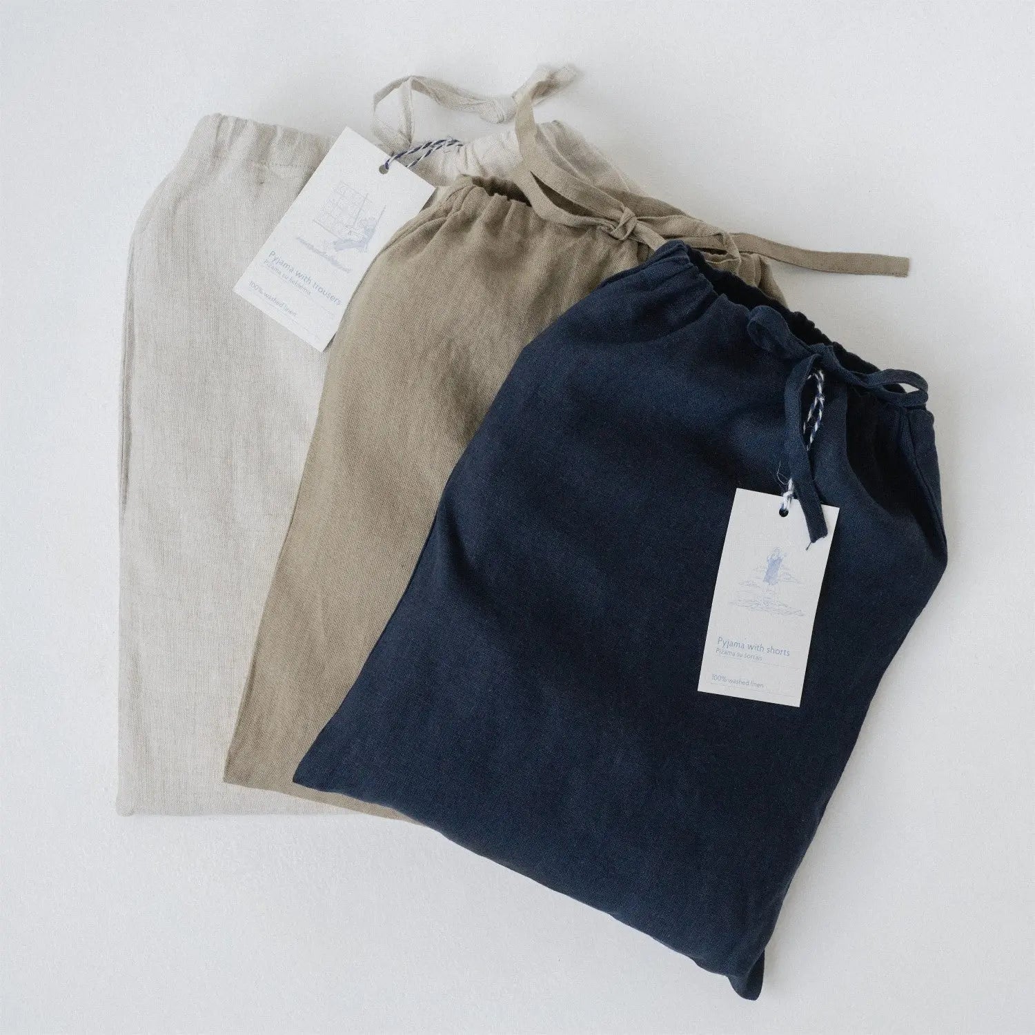 A group of linen Verbena pyjama sets in a linen bag, featuring a relaxed fit, sleeveless top, and trousers with an elastic waistband and slanted pockets. Handmade from 100% OEKO-TEX certified linen.