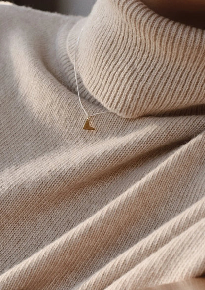 A close-up of a person wearing a Love Necklace - Gold, showcasing a heart-shaped pendant on a delicate chain. Handmade with sterling silver and 24kt gold plating.