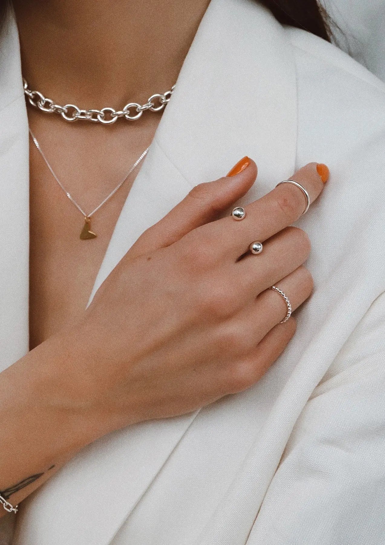 A hand wearing a Love Necklace - Gold, showcasing a heart pendant made of Sterling Silver with 24kt gold plating. Pendant dimensions: 8.5mm – 9.9mm wide, 8.10mm – 13mm high. Length: 45cm. Weight: ~2g. Hand-crafted sustainably in Lithuania and the Netherlands.