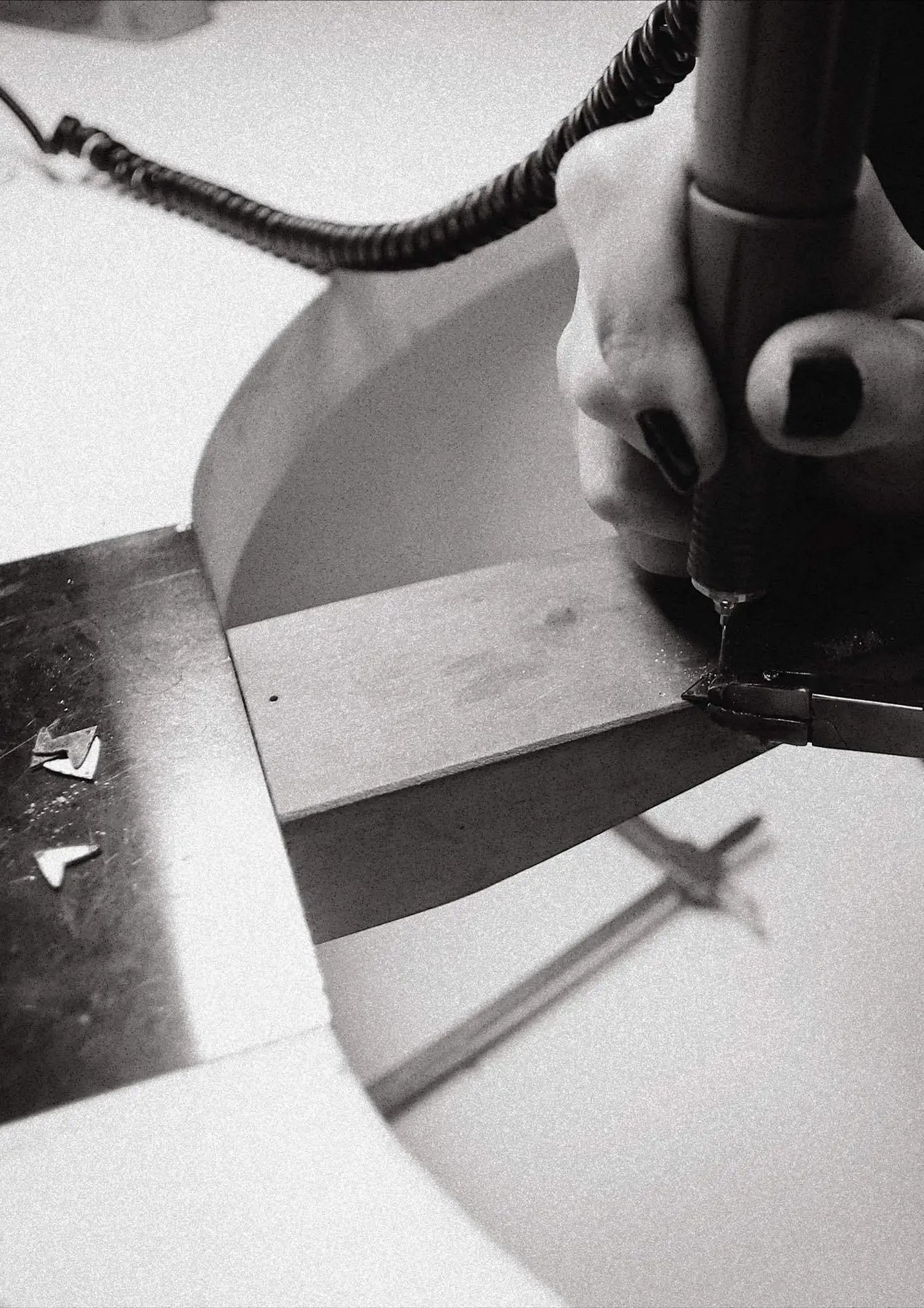 Person using a drill to cut metal, close-up of hand, black and white cable, black square on white object. Love Necklace - Gold: Sterling silver pendant, 45cm length, hand-made sustainably in Lithuania and the Netherlands.