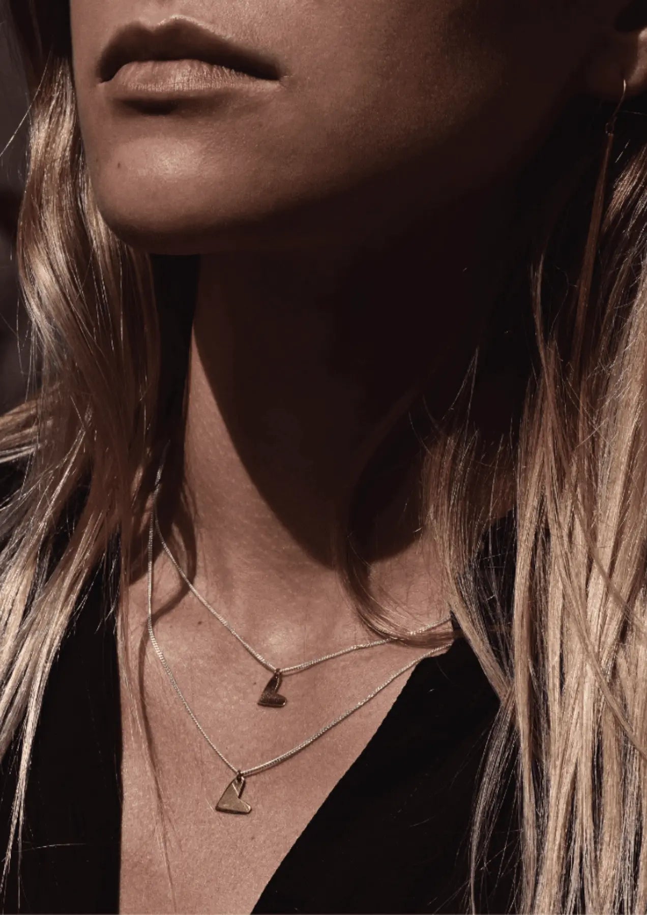 A woman wears a Love Necklace - Gold, handcrafted with Sterling Silver and 24kt gold plating, featuring an 8.5-9.9mm wide pendant. Length: 45cm. Sustainable packaging. Made in Lithuania and the Netherlands.