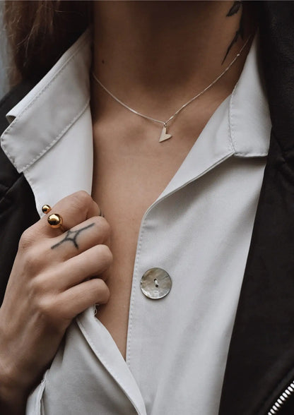 A person wearing a silver heart pendant necklace, handmade sustainably in Lithuania and the Netherlands. Pendant dimensions: 8.5mm – 9.9mm wide, 8.10mm – 13mm high. Length options: 40cm or 45cm.
