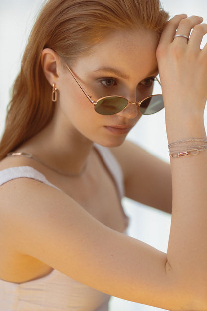 Close-up of a woman wearing sunglasses showcasing the Metropolitan Earrings, featuring sleek, understated design inspired by city vibes, crafted from 925 silver.