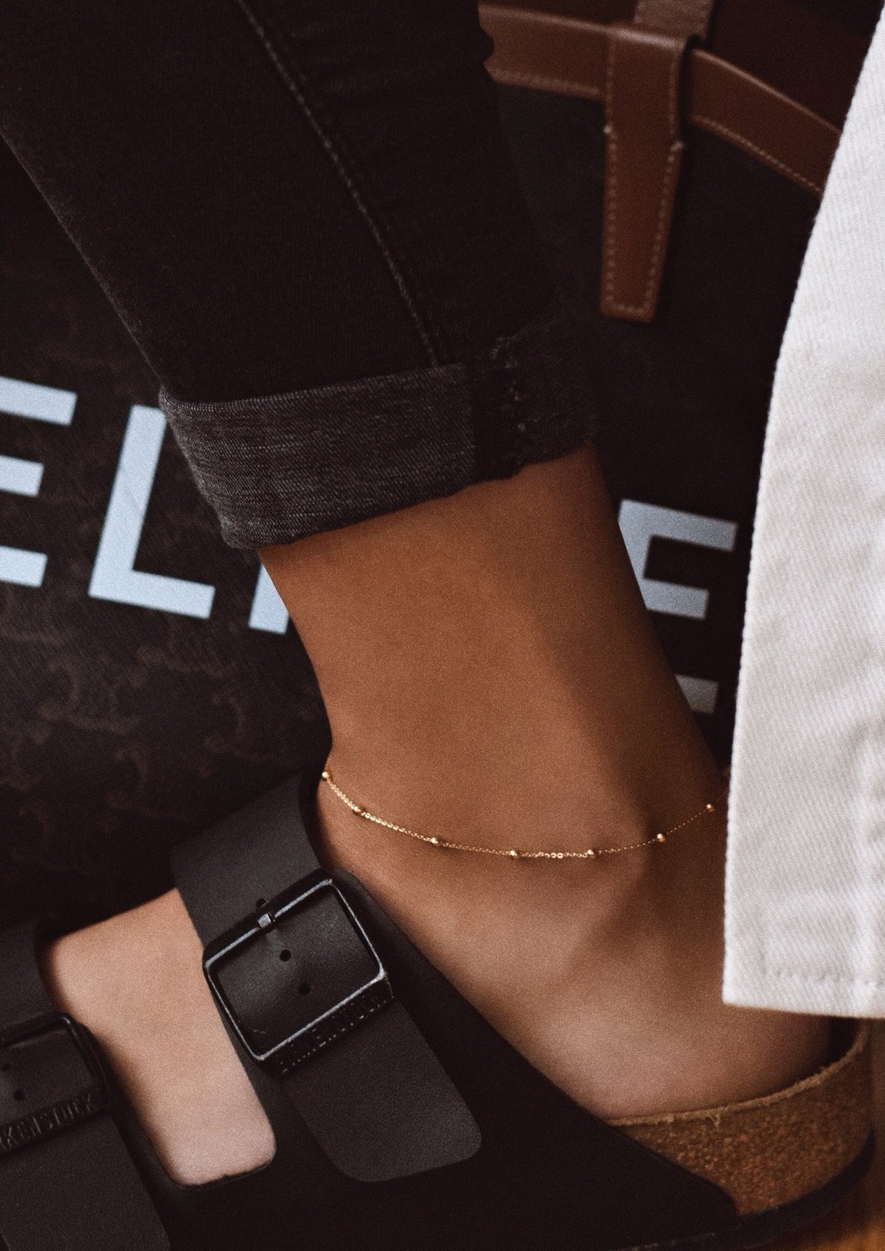 A close-up of a foot wearing the Mini Bubble Anklet - Gold, featuring a silver chain with mini bubbles. Hand-made with sterling silver coating and 24k gold plating, adjustable up to 27 cm.