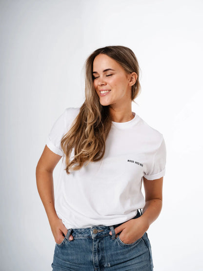 A woman in a white oversized t-shirt with her eyes closed, embodying the mood of the Need Wine T-shirt. Hand in jeans pocket visible. Organic cotton. Size chart: XS to XL.