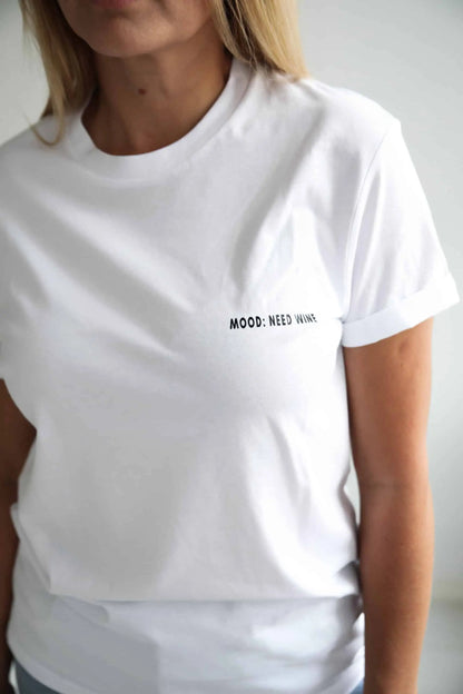 An oversized white t-shirt made of organic cotton, featuring a woman wearing it. Product title: Mood: Need wine T-shirt.