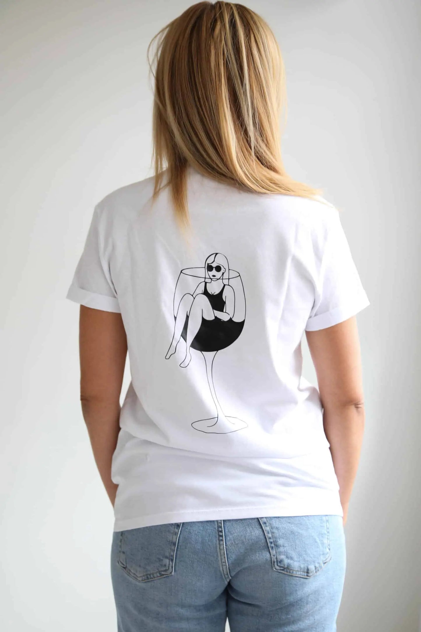 An oversized white t-shirt featuring a black and white wine glass design, perfect for wine enthusiasts. Made of organic cotton. Size chart available.