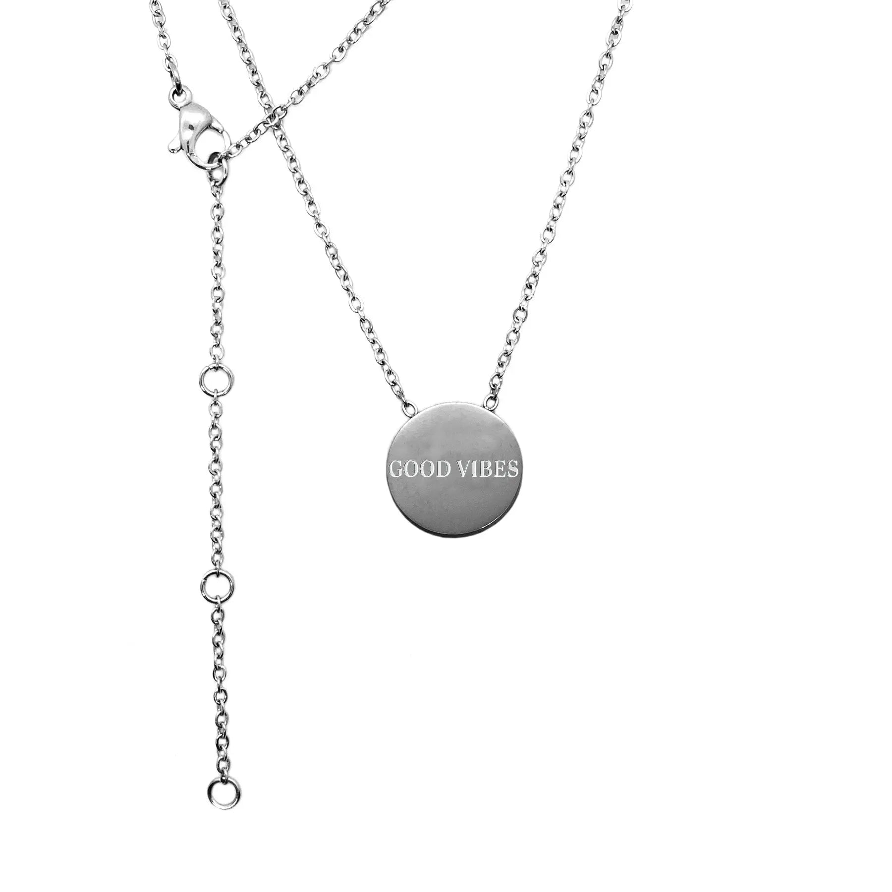 A silver necklace with a circular medallion, featuring Good Vibes text. Stainless steel, 49 cm length, 18 mm medallion size. Durable and polished for lasting wear.