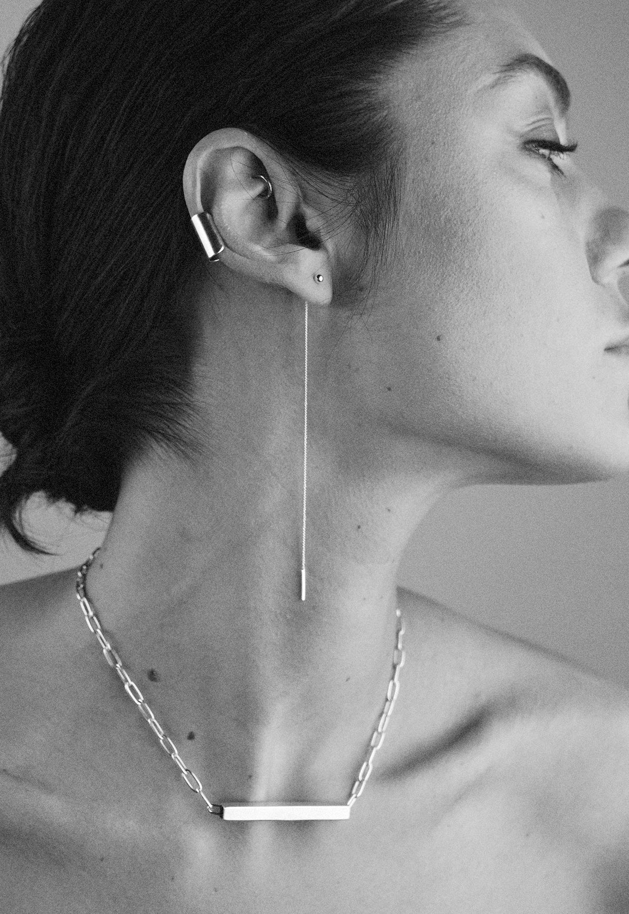 A woman wearing Pin Up Threader Chain Earrings in silver, showcasing delicate chain design threading through ears for a classy, minimalist look. Hand-made in Lithuania, 11 cm long.