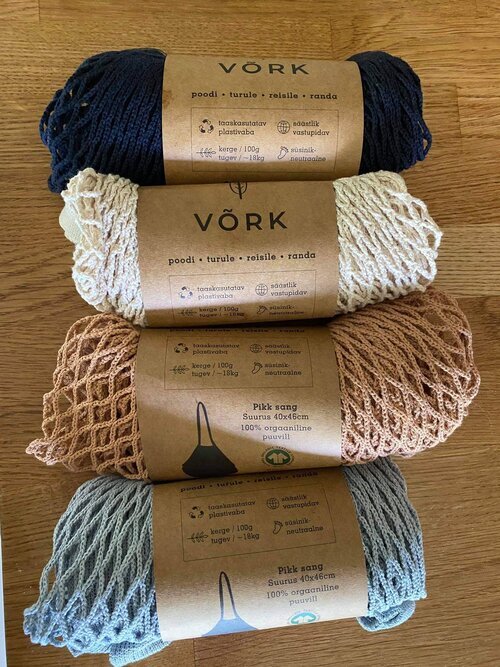 A group of yarn rolls on a table, showcasing Plastic-free Net Bag. Organic cotton, 15 kg capacity, 43 x 45 cm size, 100 gr weight. Strong handles, visible contents.