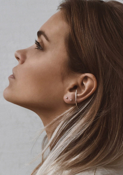 Close-up of Radius Earrings - Sterling Silver 925, showcasing elegant lines and circles on a person's ear with push-back clasps. Hand-made sustainably in Lithuania and the Netherlands.