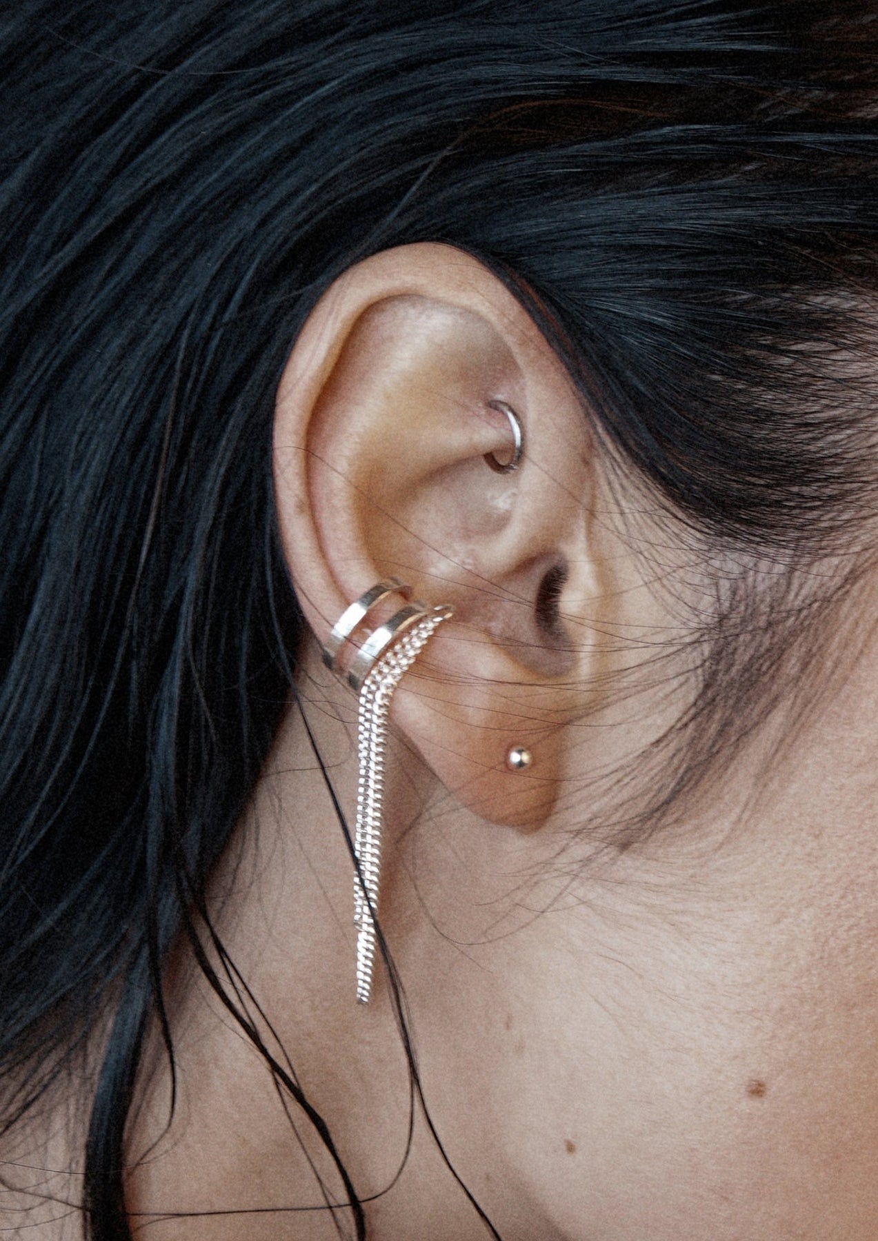 Close-up of Revolve Ear Cuff in sterling silver, featuring a double chain design. Handcrafted accessory for non-pierced ears, with a sleek, edgy look.