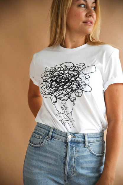 A woman in an oversized Ssshhh! T-shirt with a black design, paired with jeans. Close-up of face details not visible. Size chart and washing instructions provided.