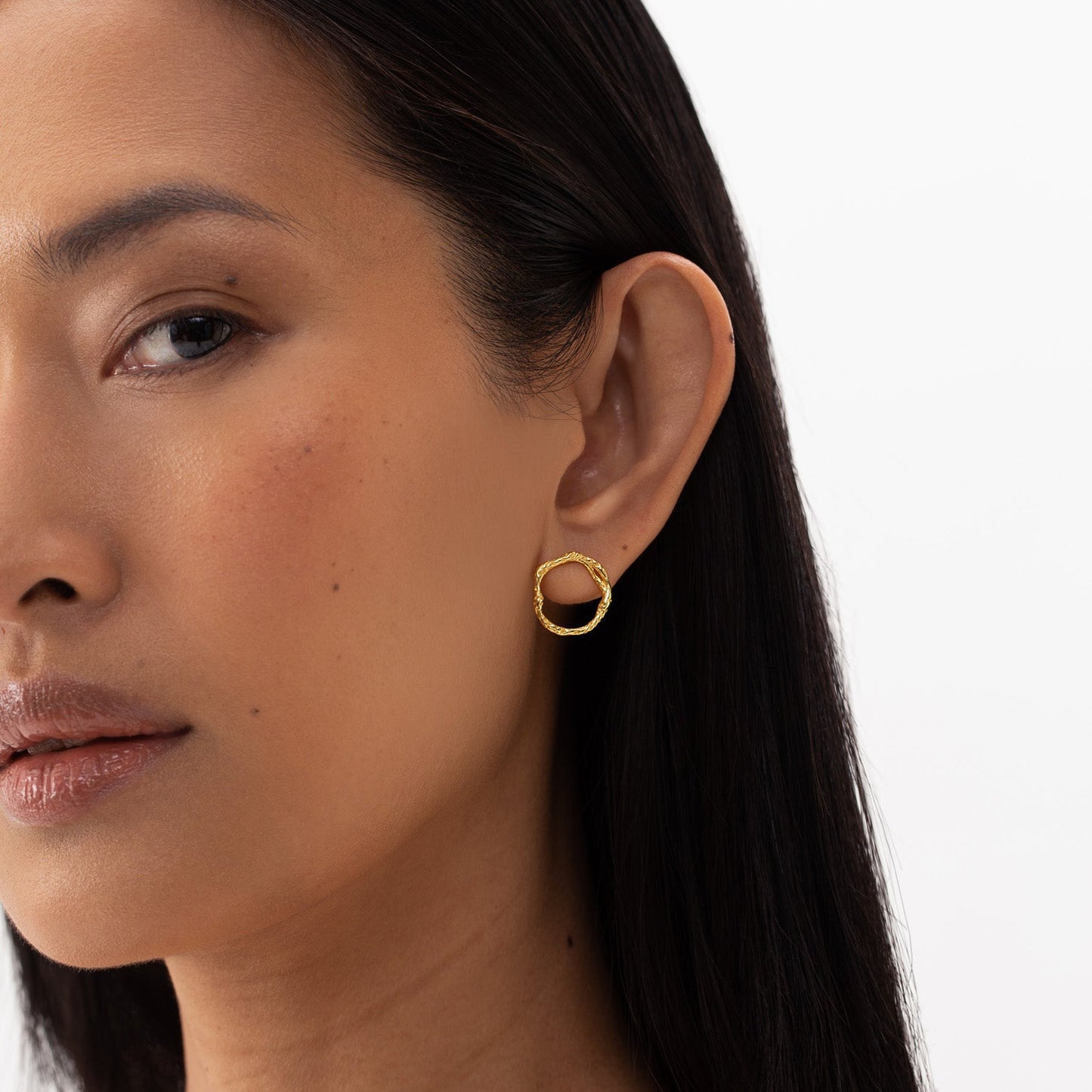 Stud Earrings ECHO - Gold: Close-up of a woman wearing minimalist circle-shaped golden earrings, hypoallergenic and made from recycled silver, 18k gold plated. Size: 16 x 17 mm.