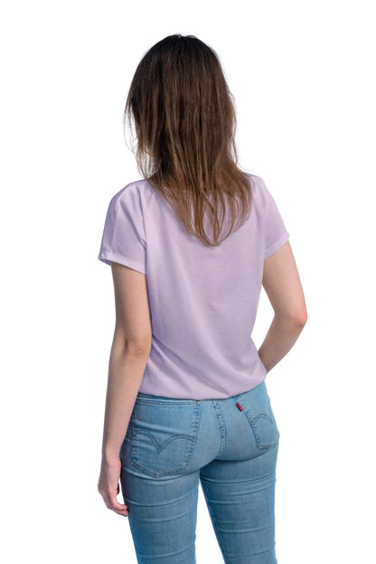 A woman in a tan-through lilac spacious T-shirt, showcasing a comfortable cut for outdoor activities. Fabric allows healthy tanning with UVA penetration. Sizes XS-XXL.